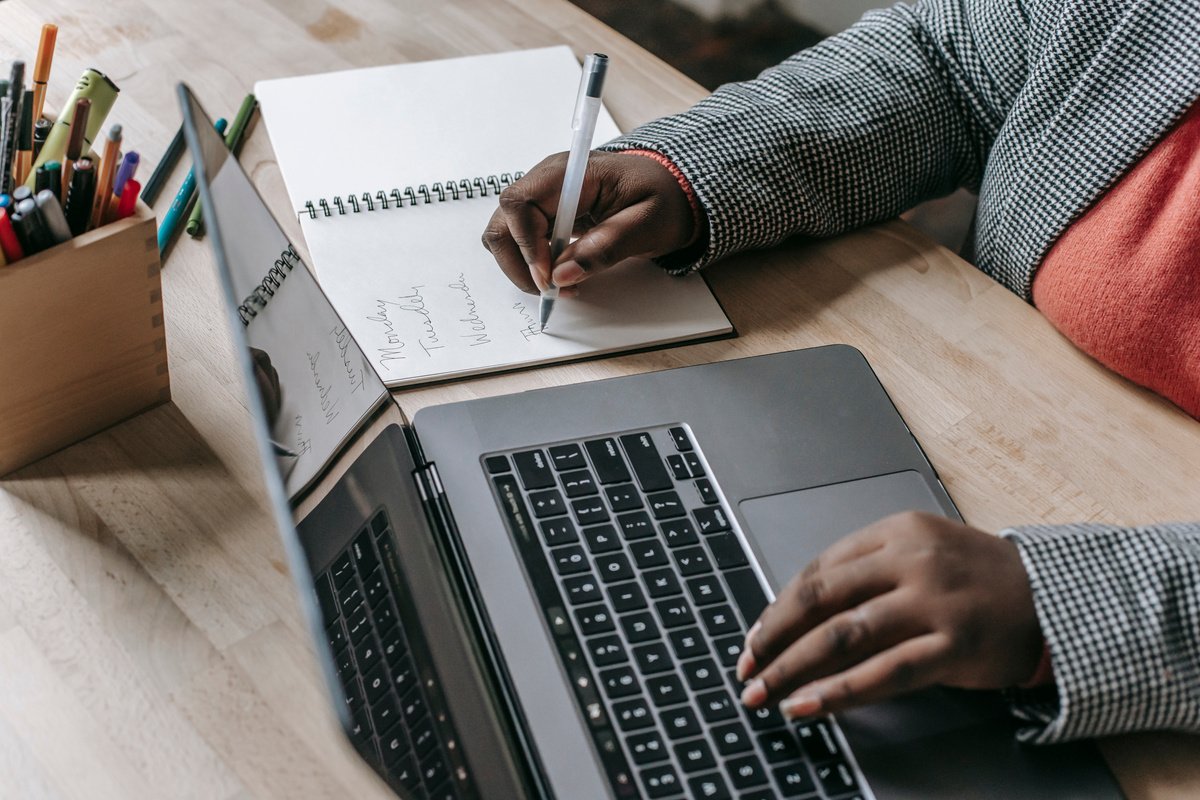 Crop black woman taking notes from laptop