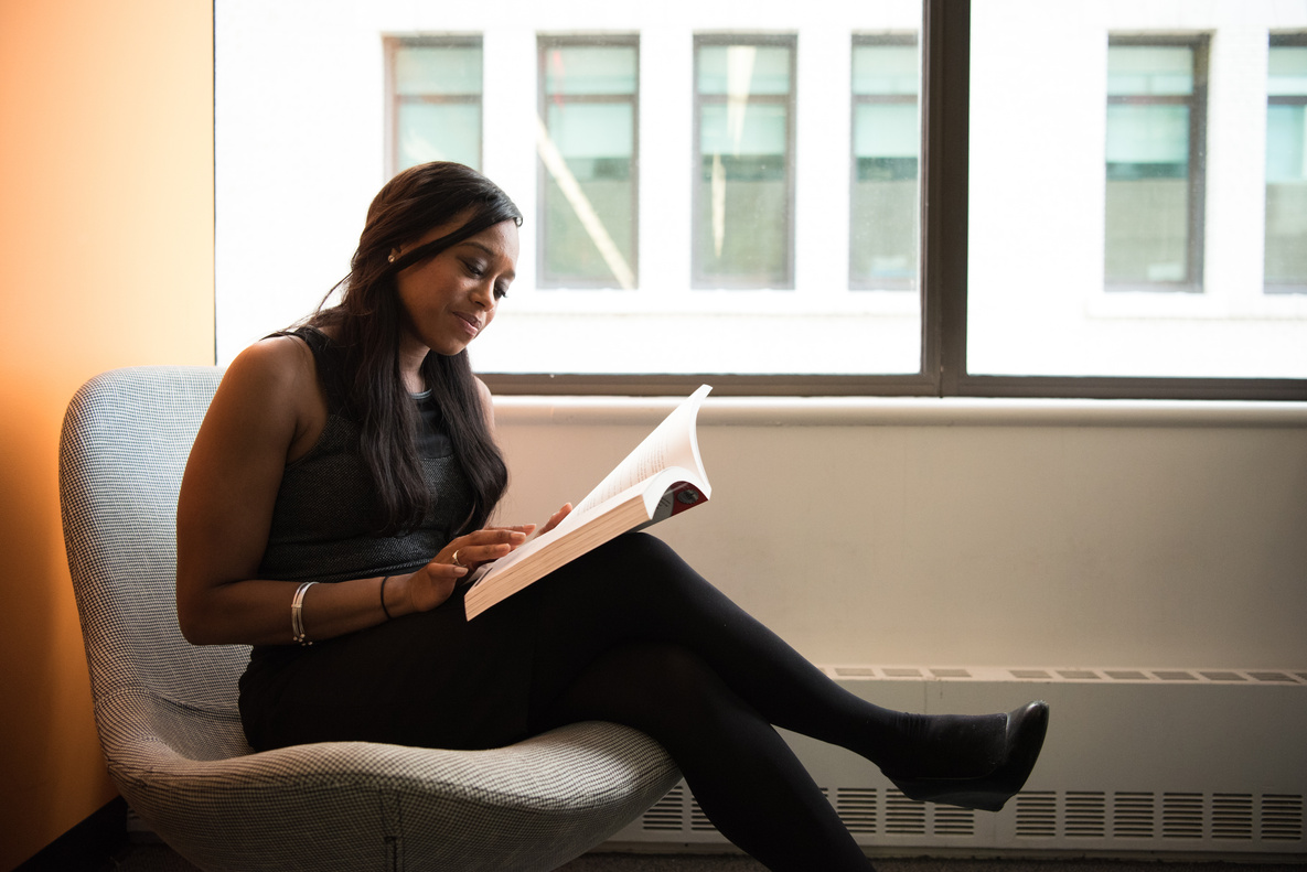 Woman Sitting and Reading Book Wearing Black