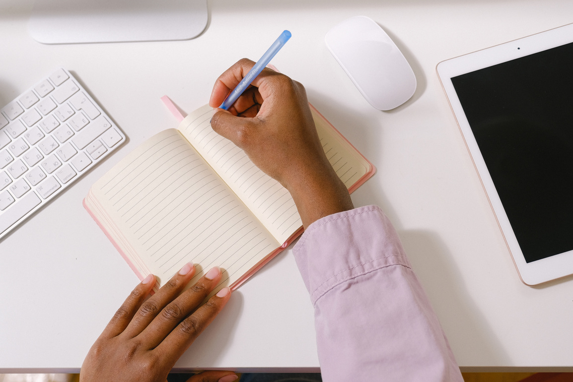 Black woman with pen taking notes in planner